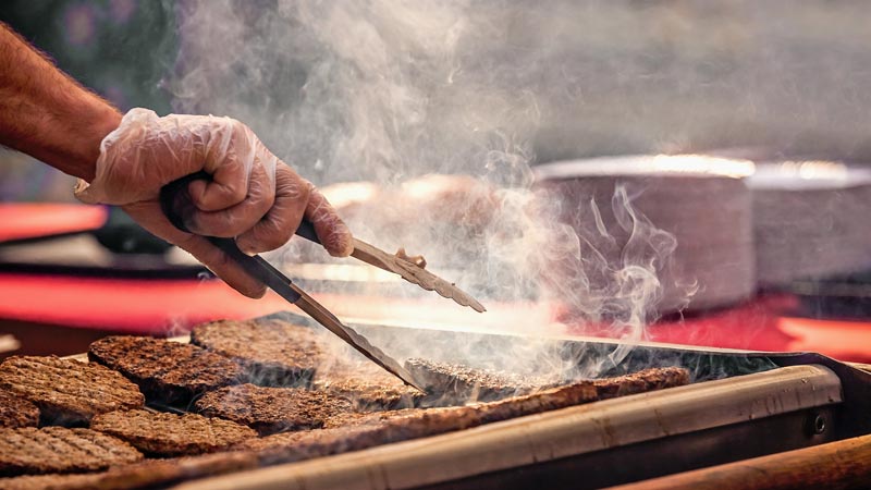 Mann wendet Fleisch auf einem Grill